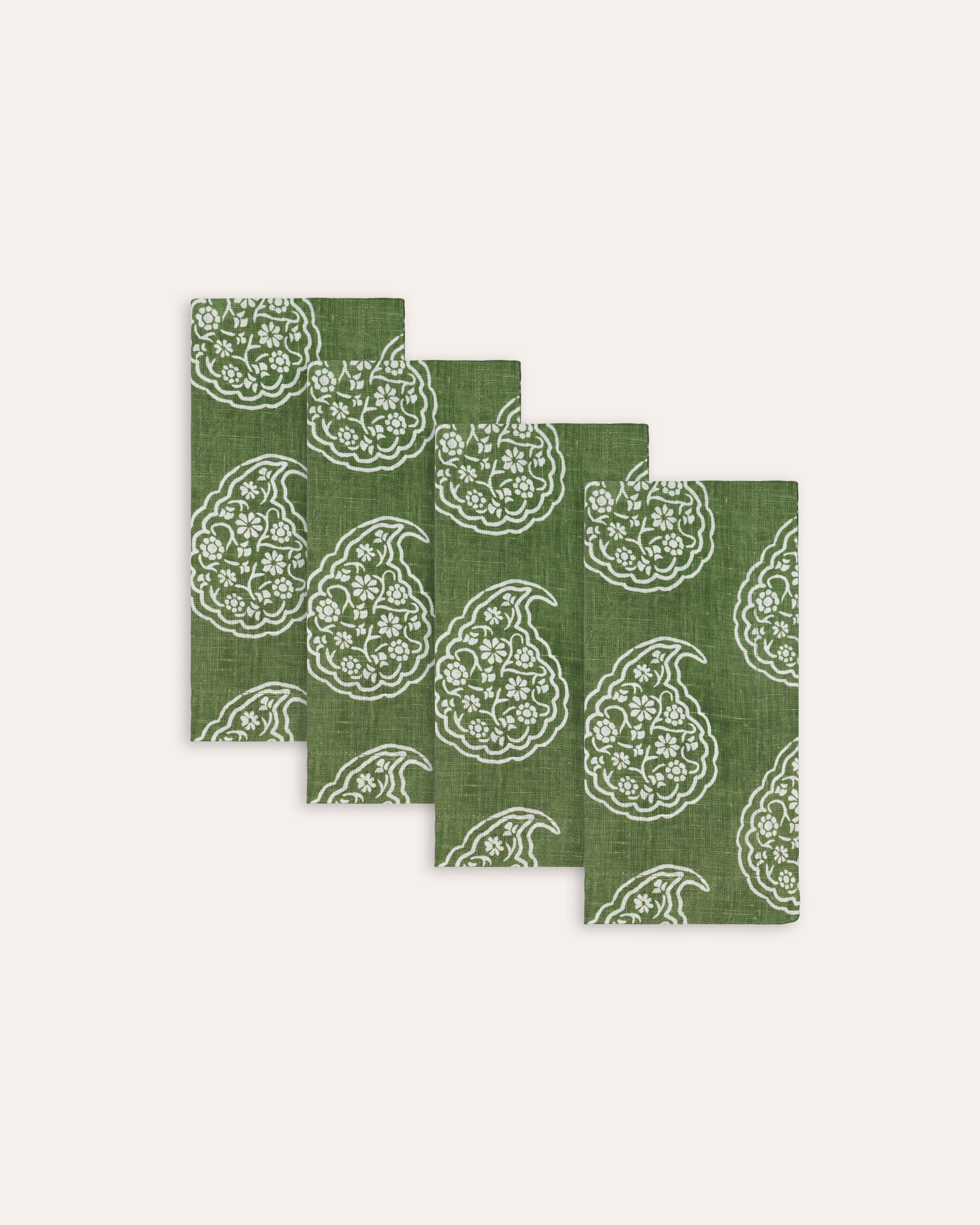 Set of four green and white patterned napkins on a white background