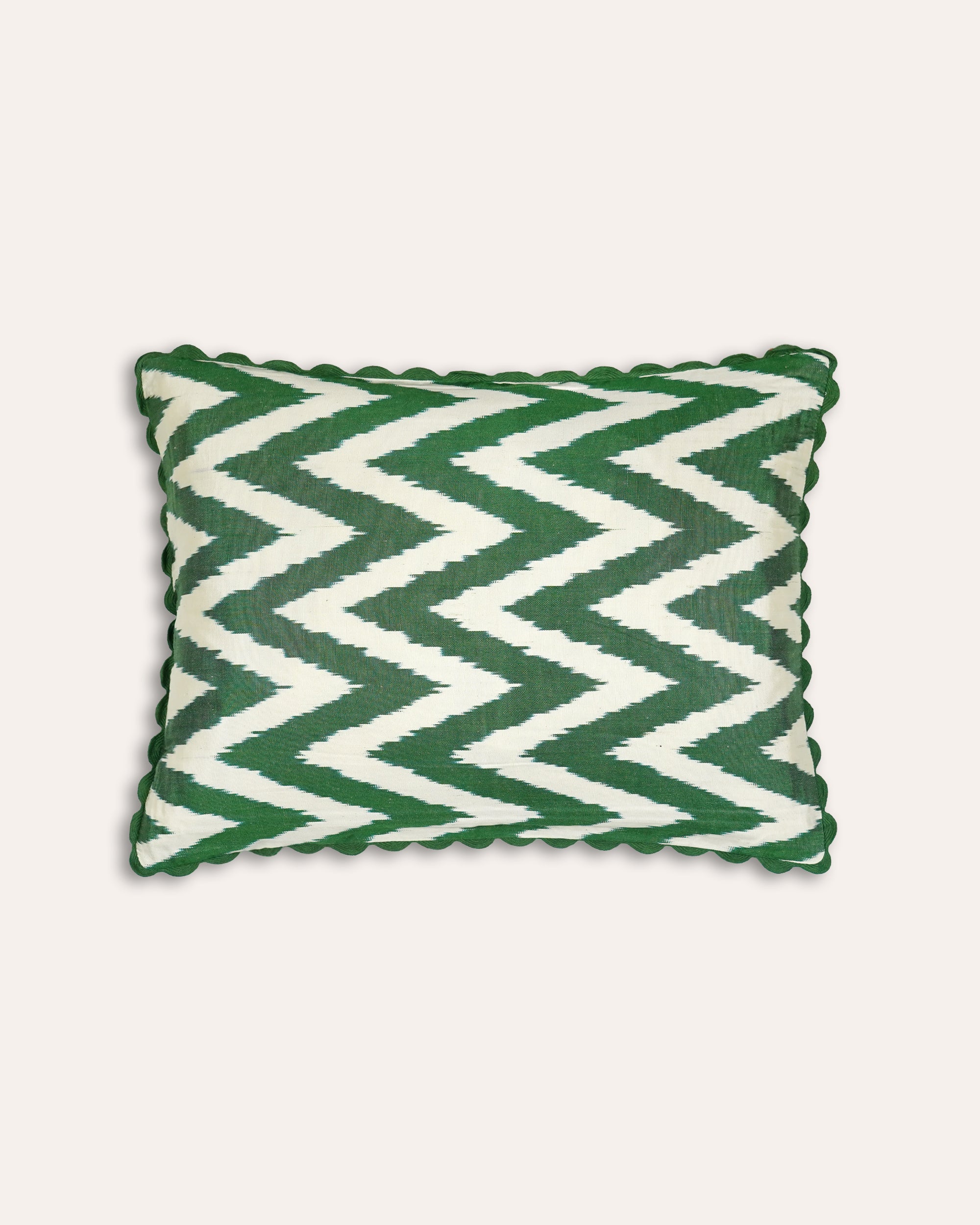 Green and white chevron patterned cushion on a light beige background