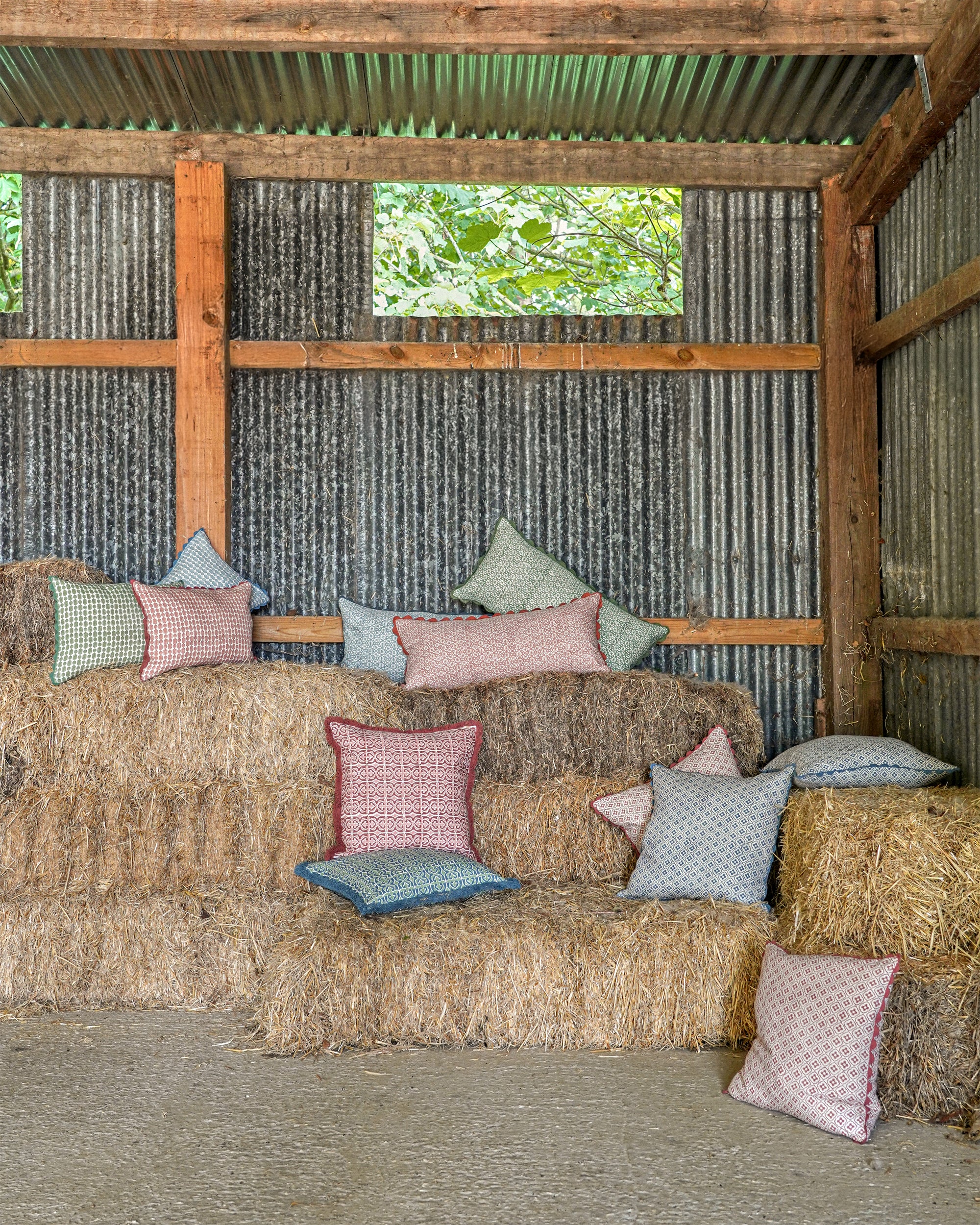 Sofa made of hay with colorful cushions in a rustic setting