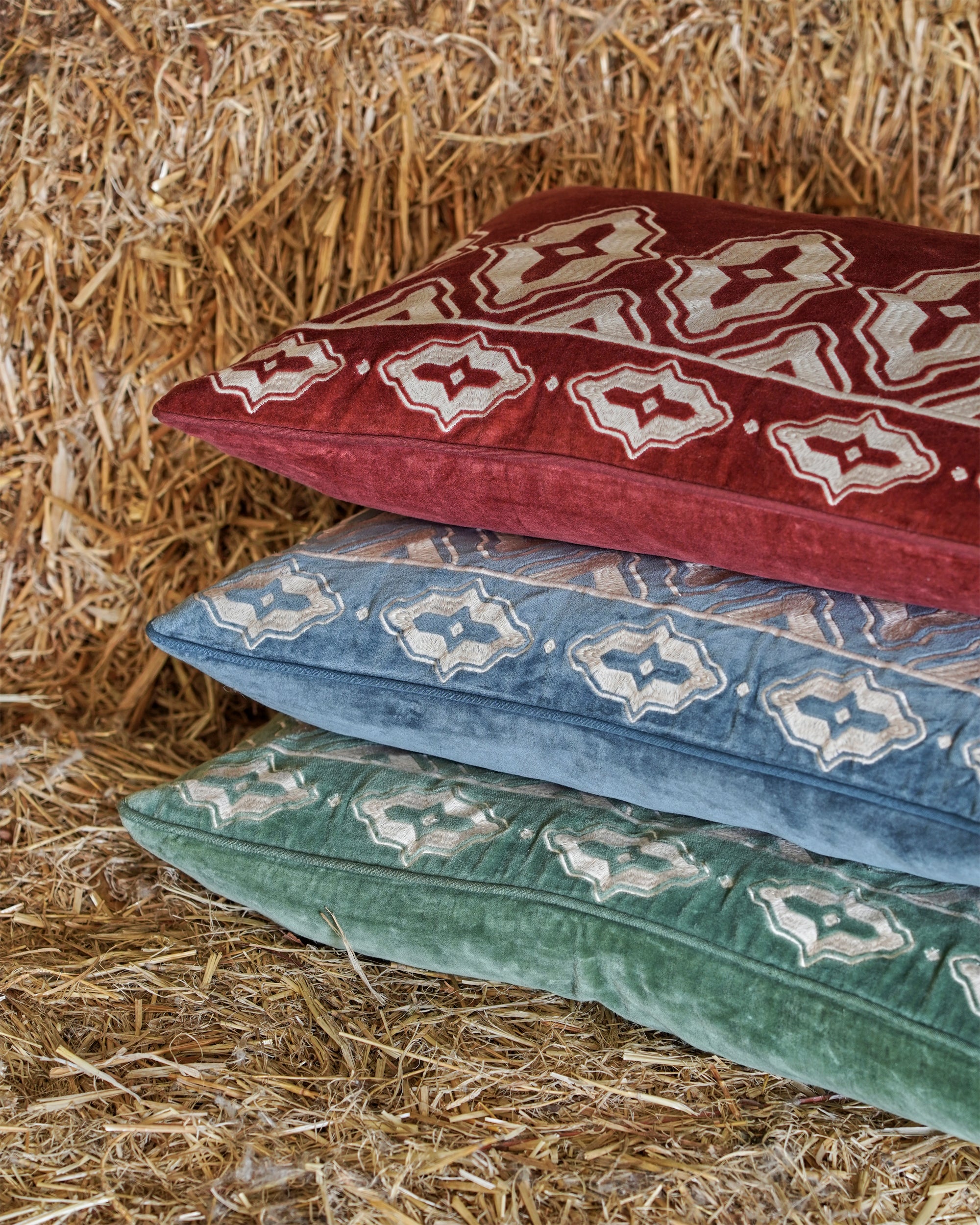 Decorative pillows with intricate patterns on a hay background