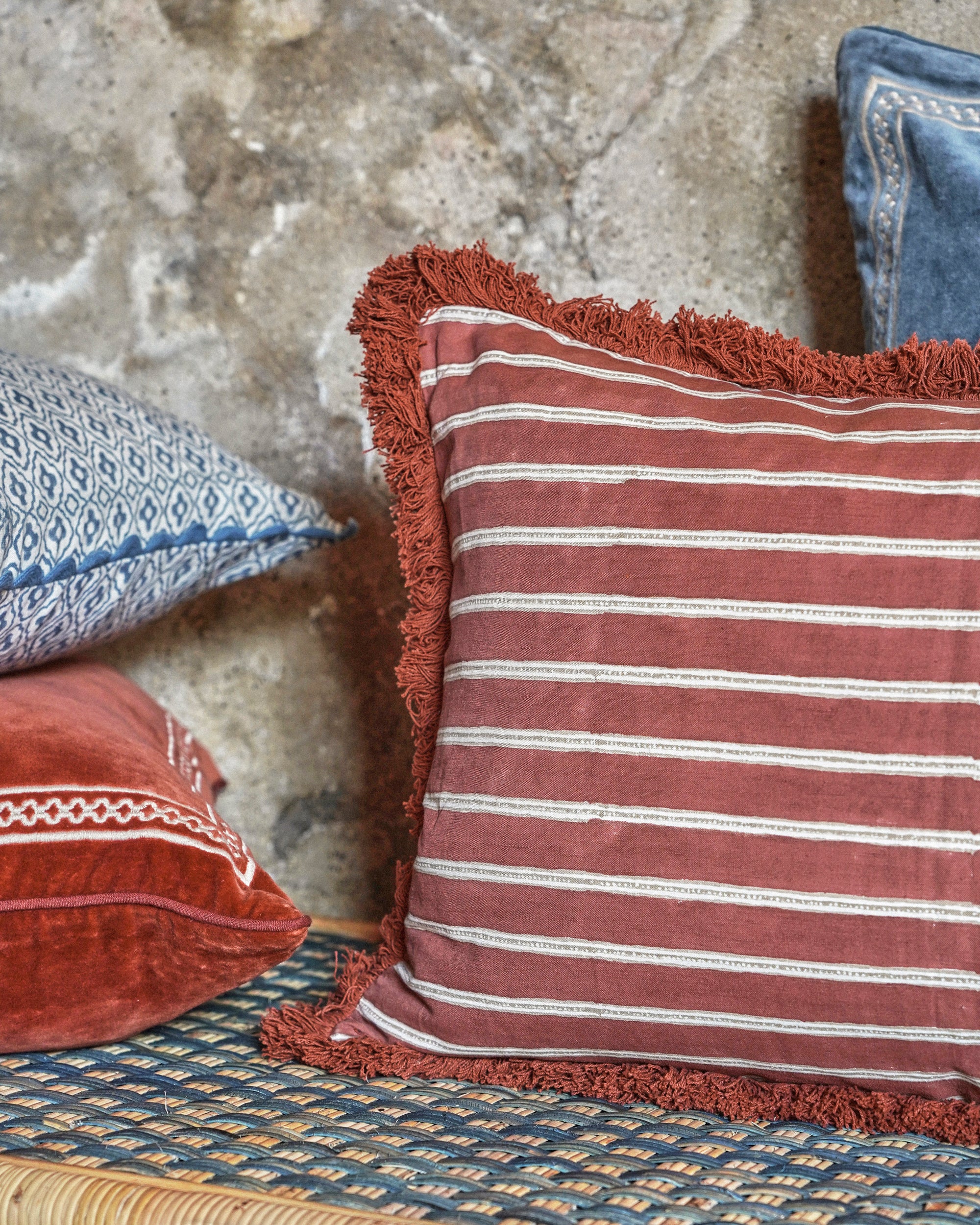 Red and white striped pillow with frayed edges on a textured surface