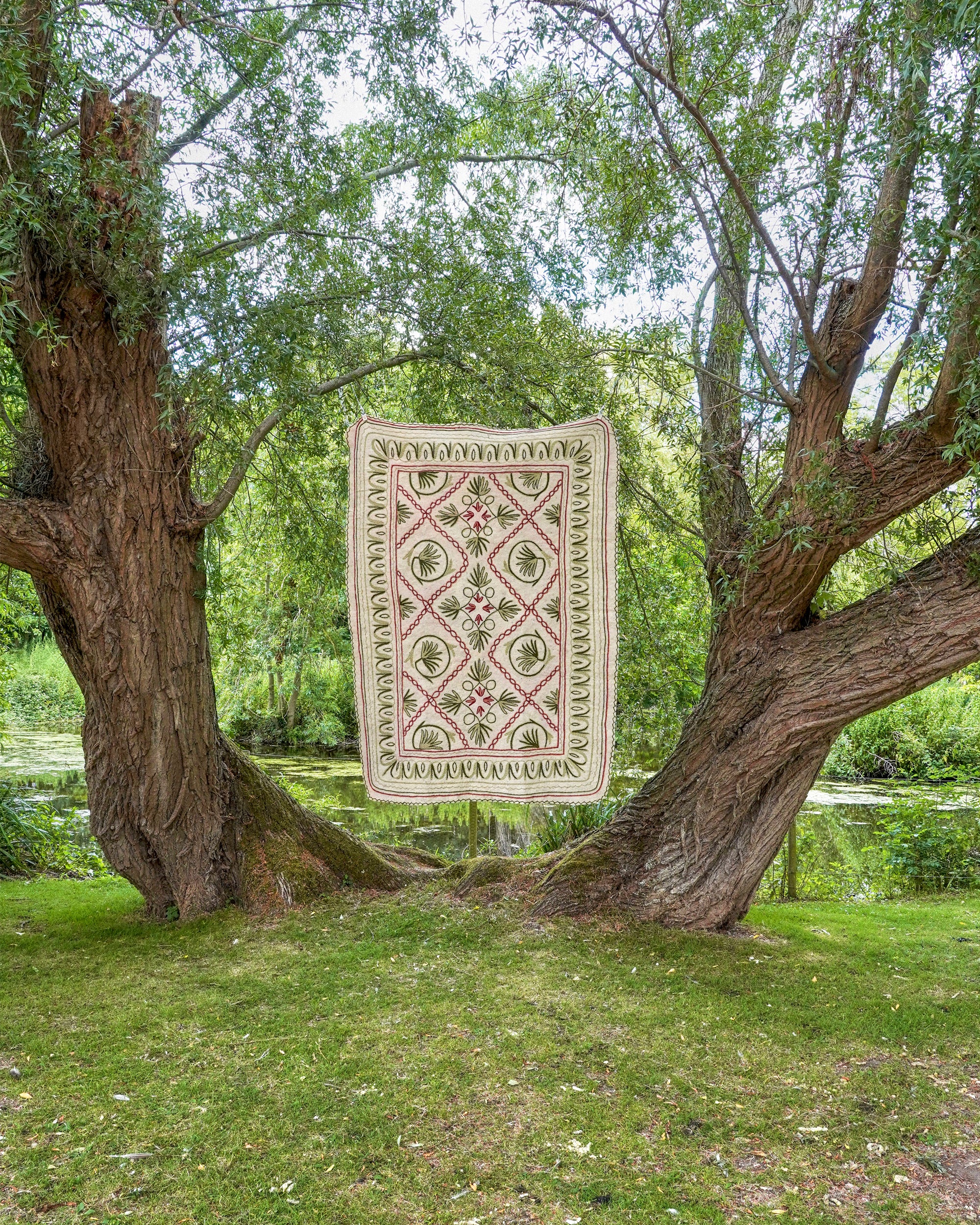 Decorative rug with geometric pattern hanging between two trees in a park