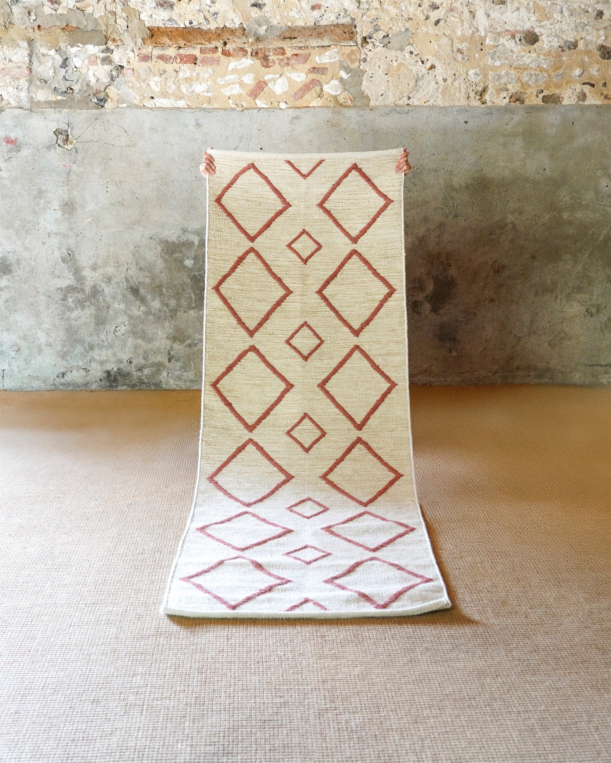 Small rug with red geometric pattern on a stone floor