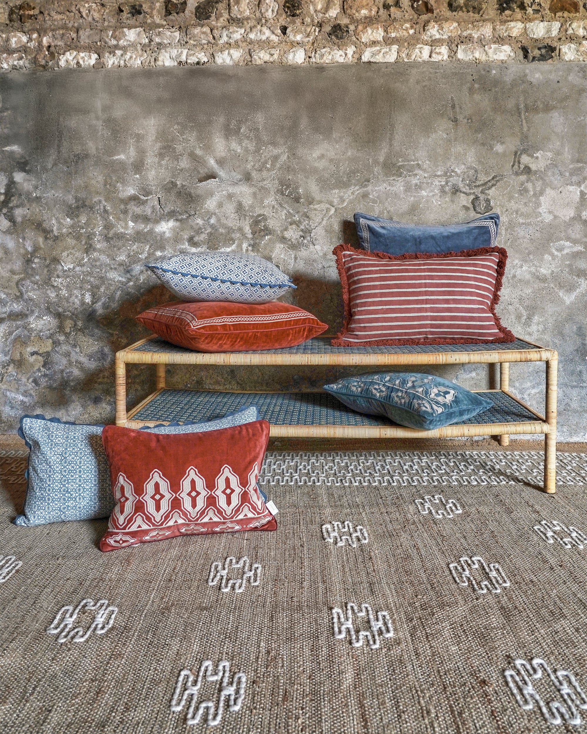 Woven bench with colorful cushions against a textured wall.