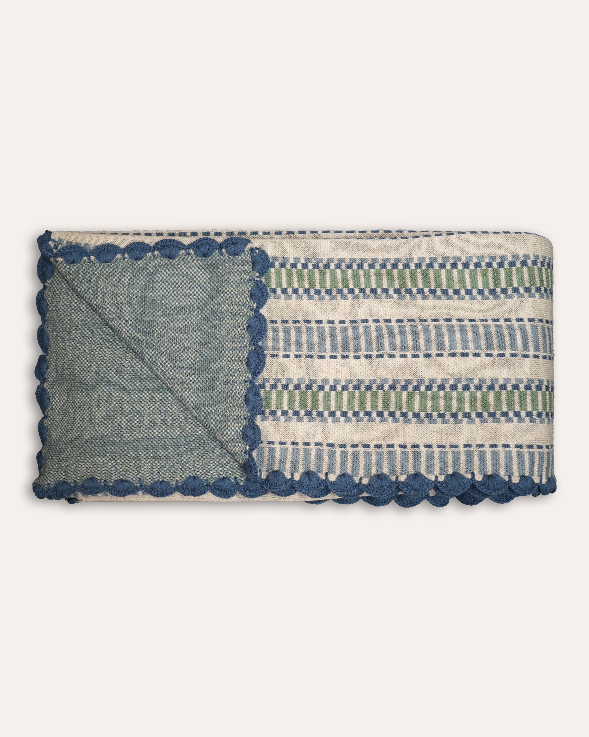 Blue and green throw with striped pattern and pom-pom trim on a white background