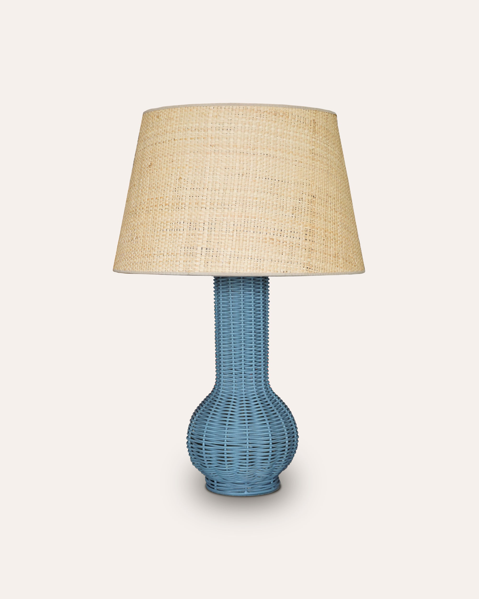 Table lamp with blue woven base and beige lampshade on a white background