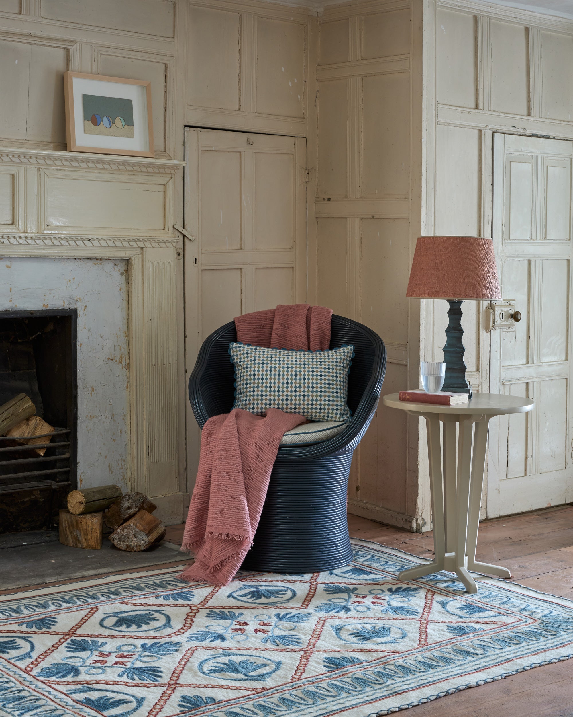 Cozy living room with a fireplace, chair with pink blanket, and lamp.